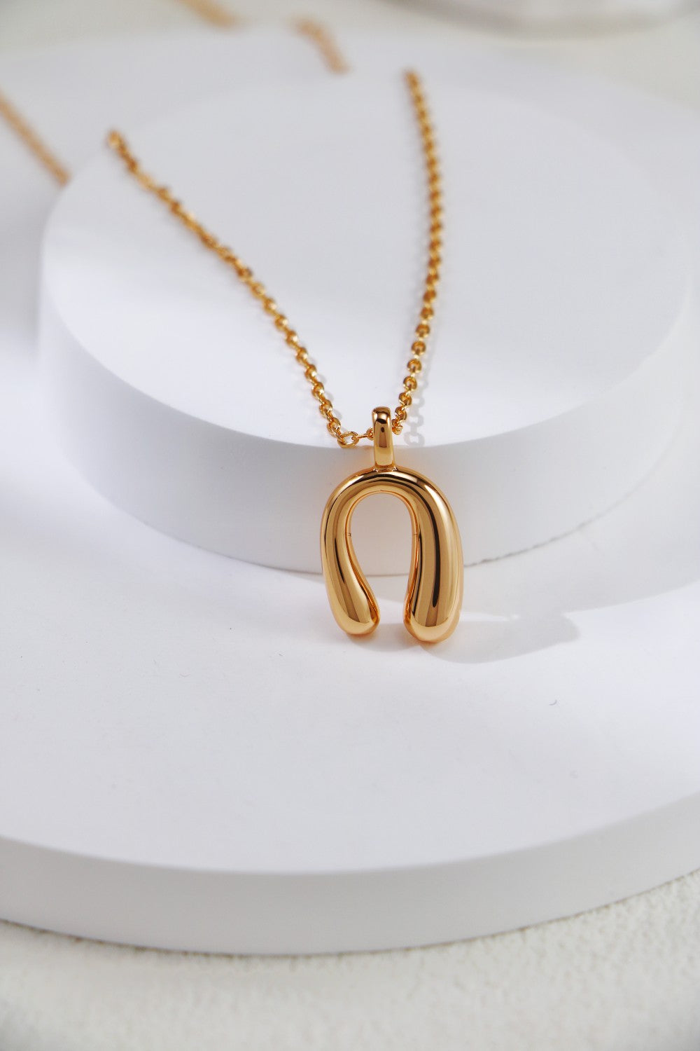 A gold necklace featuring a delicate horseshoe charm pendant, symbolizing luck and elegance.