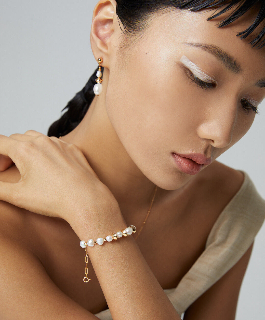 Model with gold bracelet and dangling earrings.