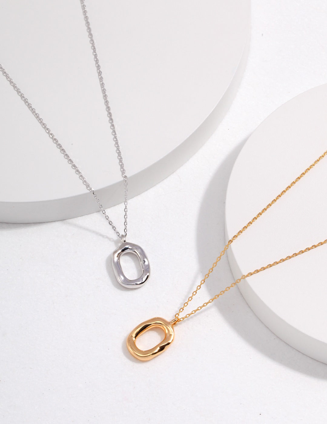 Two sleek gold and silver necklaces featuring elegant circle pendants, showcasing a modern and stylish design.