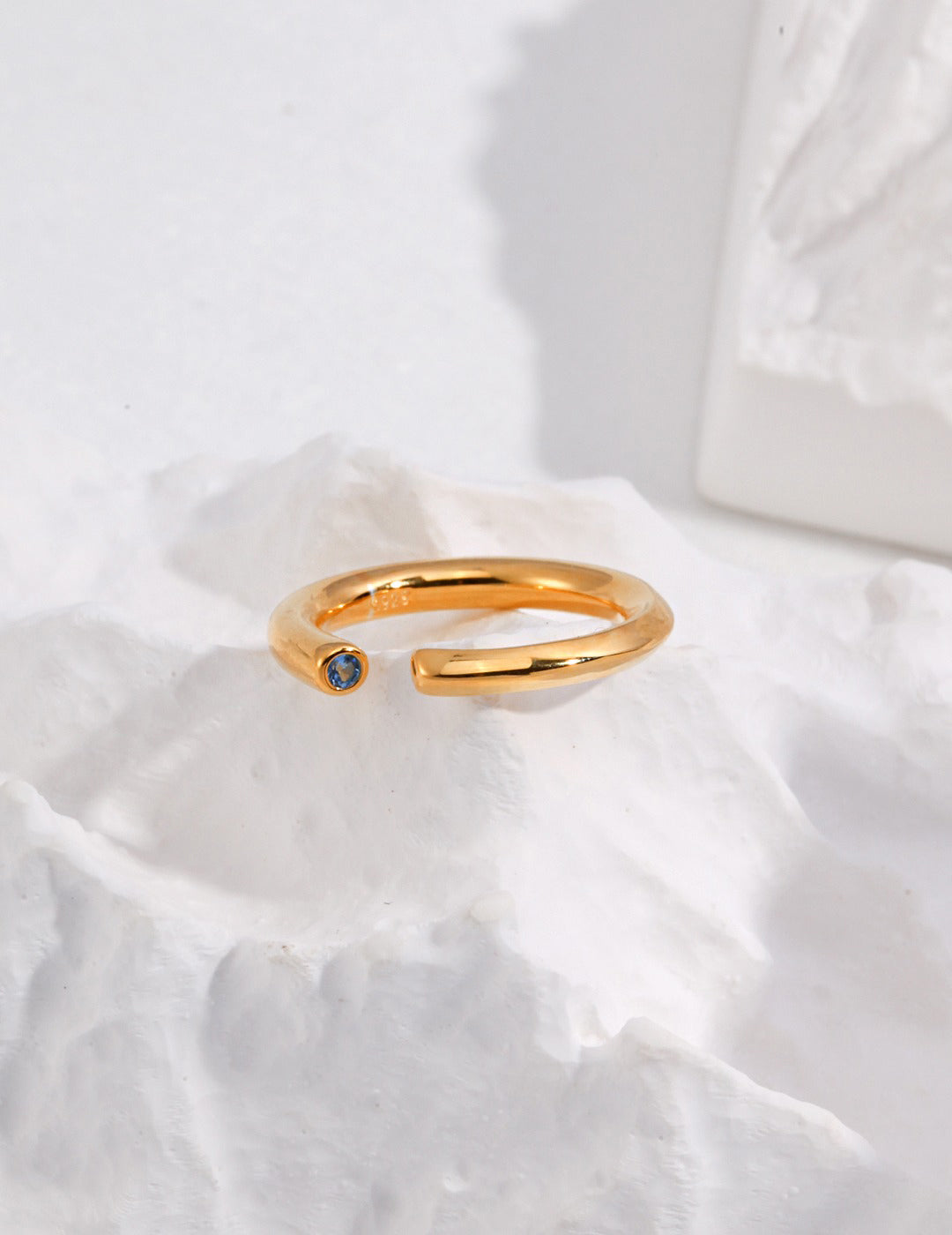 Dainty gold ring with stunning blue aquamarine stone on rock.
