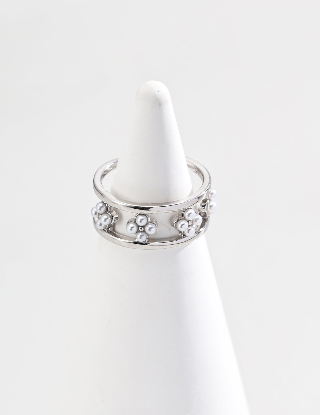 A stunning silver ring featuring shell pearls, elegantly placed atop a textured cone, showcasing its brilliance and design.