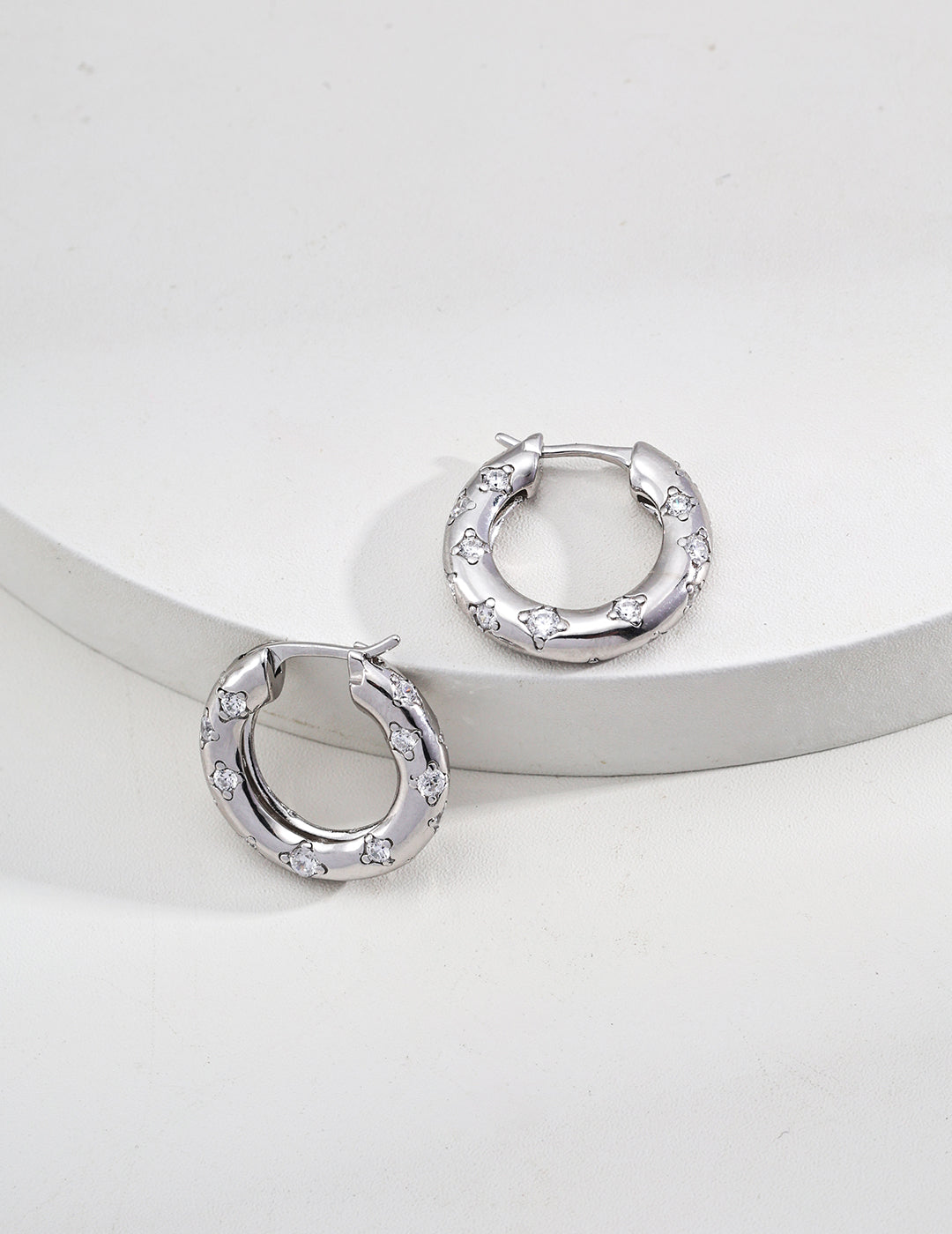 Silver hoop earrings embellished with dazzling stones on top, offering a chic and sophisticated accessory option.