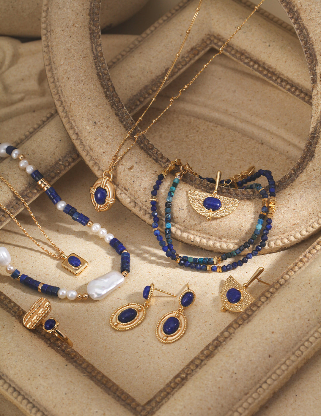 A stunning collection of gold jewelry adorned with beautiful blue stones, including a cobalt blue lapis lazuli necklace with freshwater pearls.