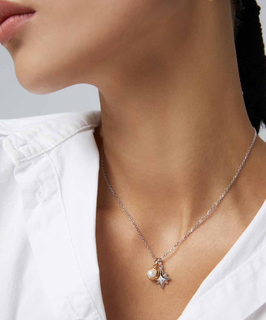 Female in white top accessorized with star necklace on silver chain.