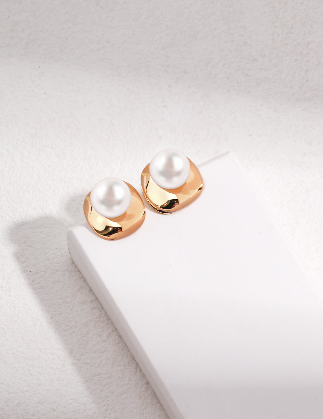 Two elegant gold-plated earrings featuring a pearl on each side, exuding sophistication and style.