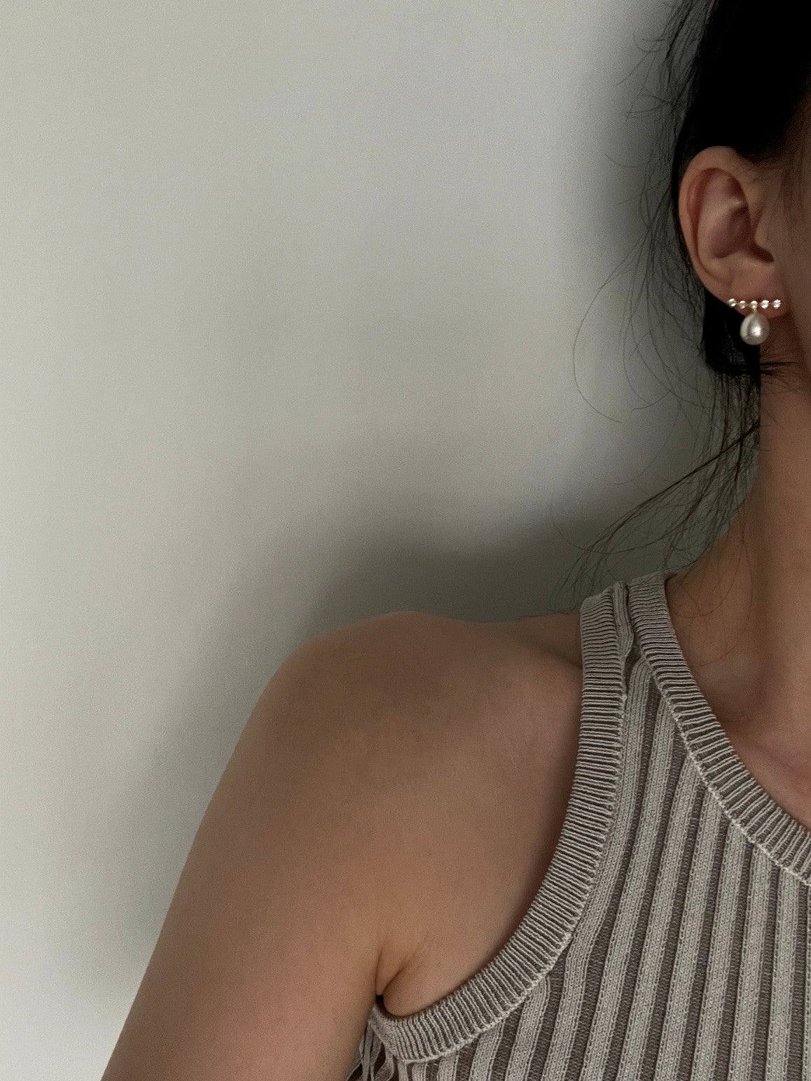 A woman in a striped top and earrings, showcasing lustrous rice pearl sparkly earrings.