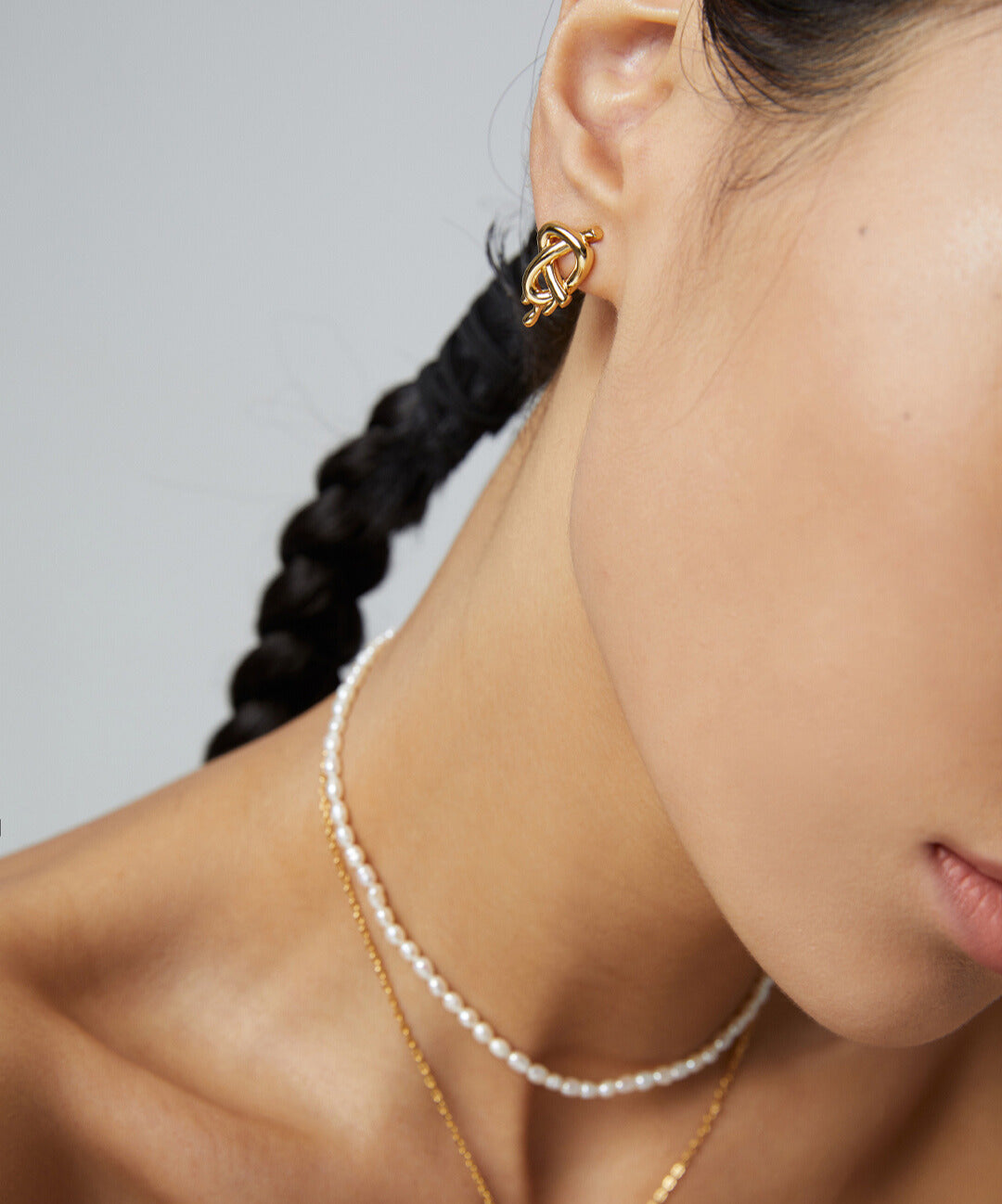 Woman in gold plated earrings and freshwater pearls necklace.