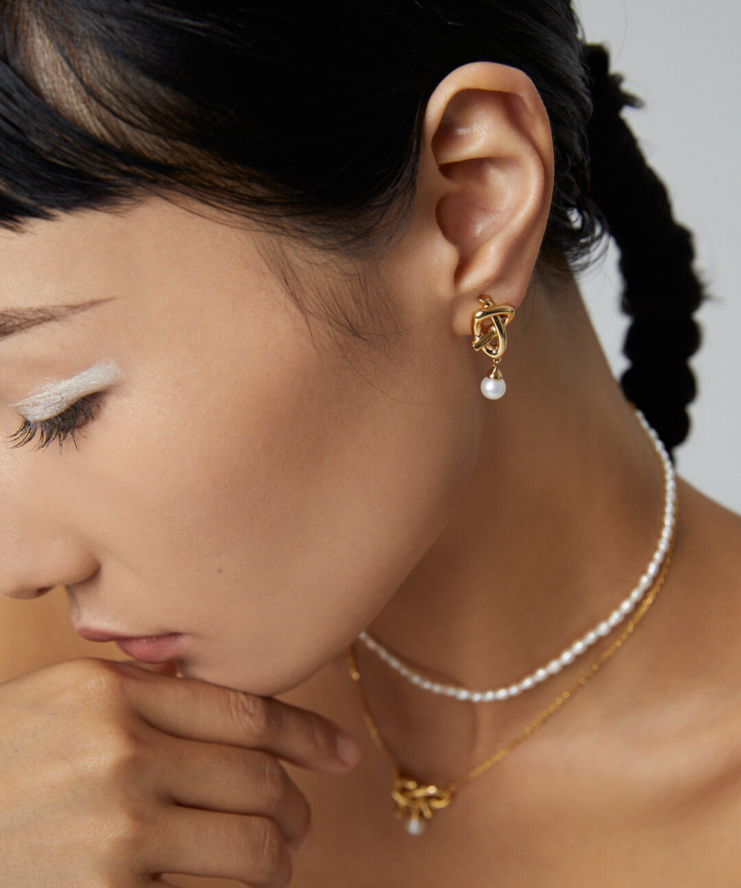 Elegant lady adorned with gold plated earrings and pearls.