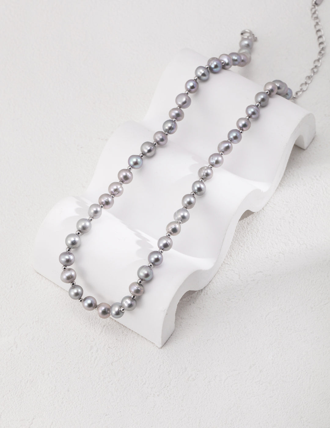 An elegant necklace showcasing a beautiful grey freshwater pearl bead on a clean white background.
