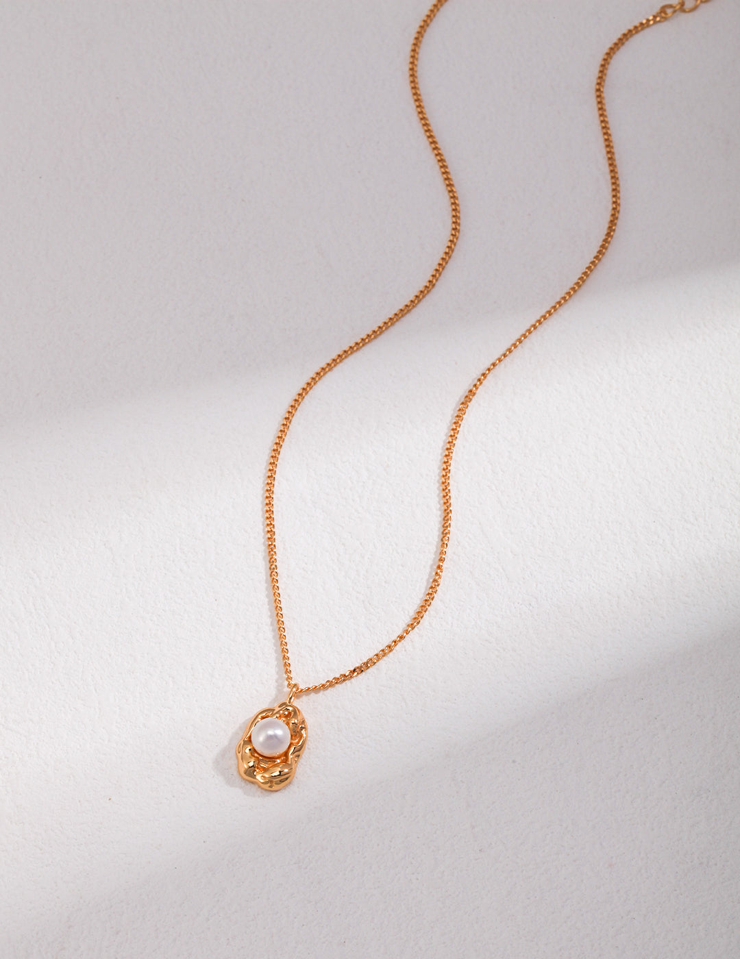 A stunning gold necklace adorned with a delicate pearl charm.