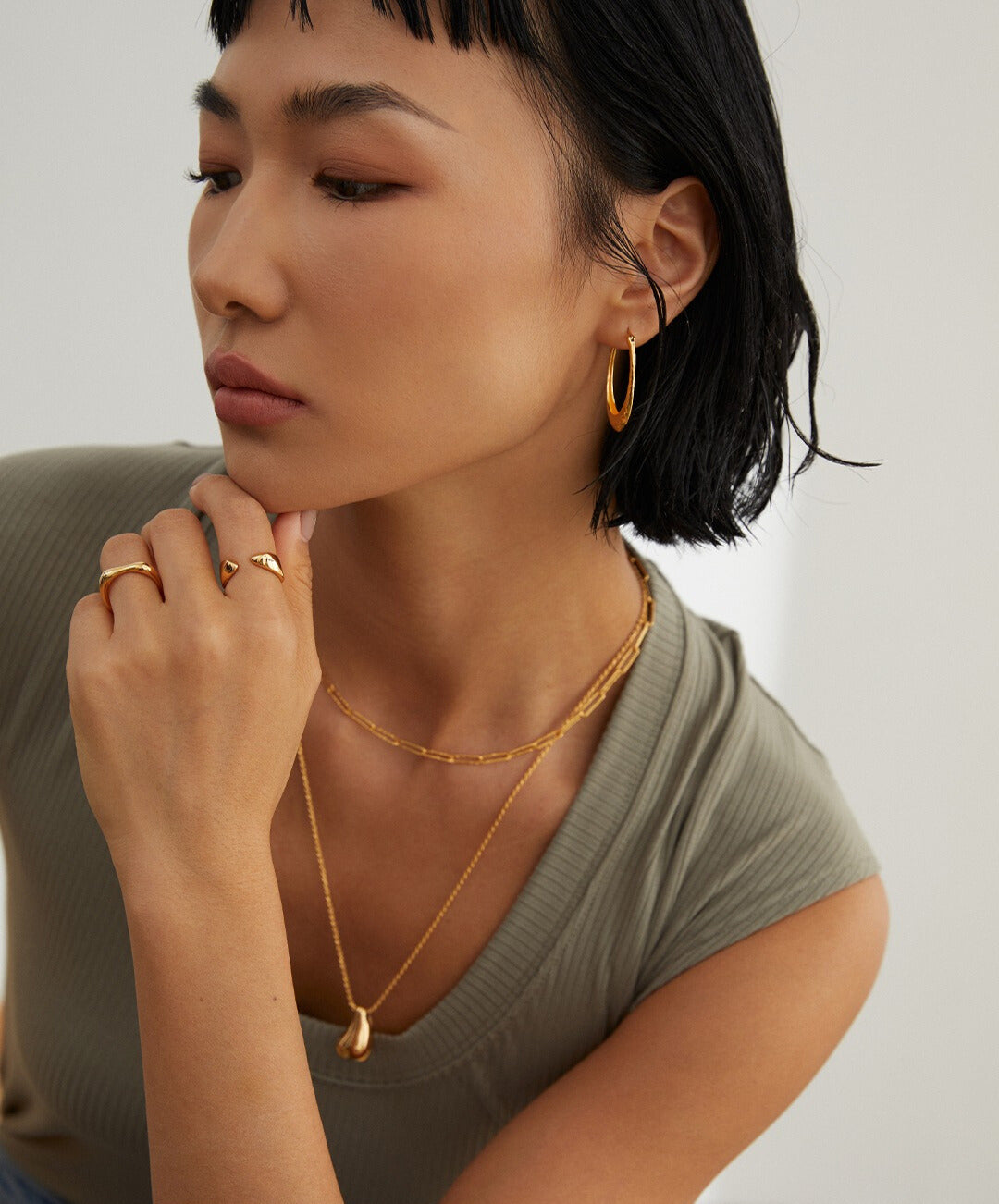 A woman wearing gold link chain necklaces and matching earrings.
