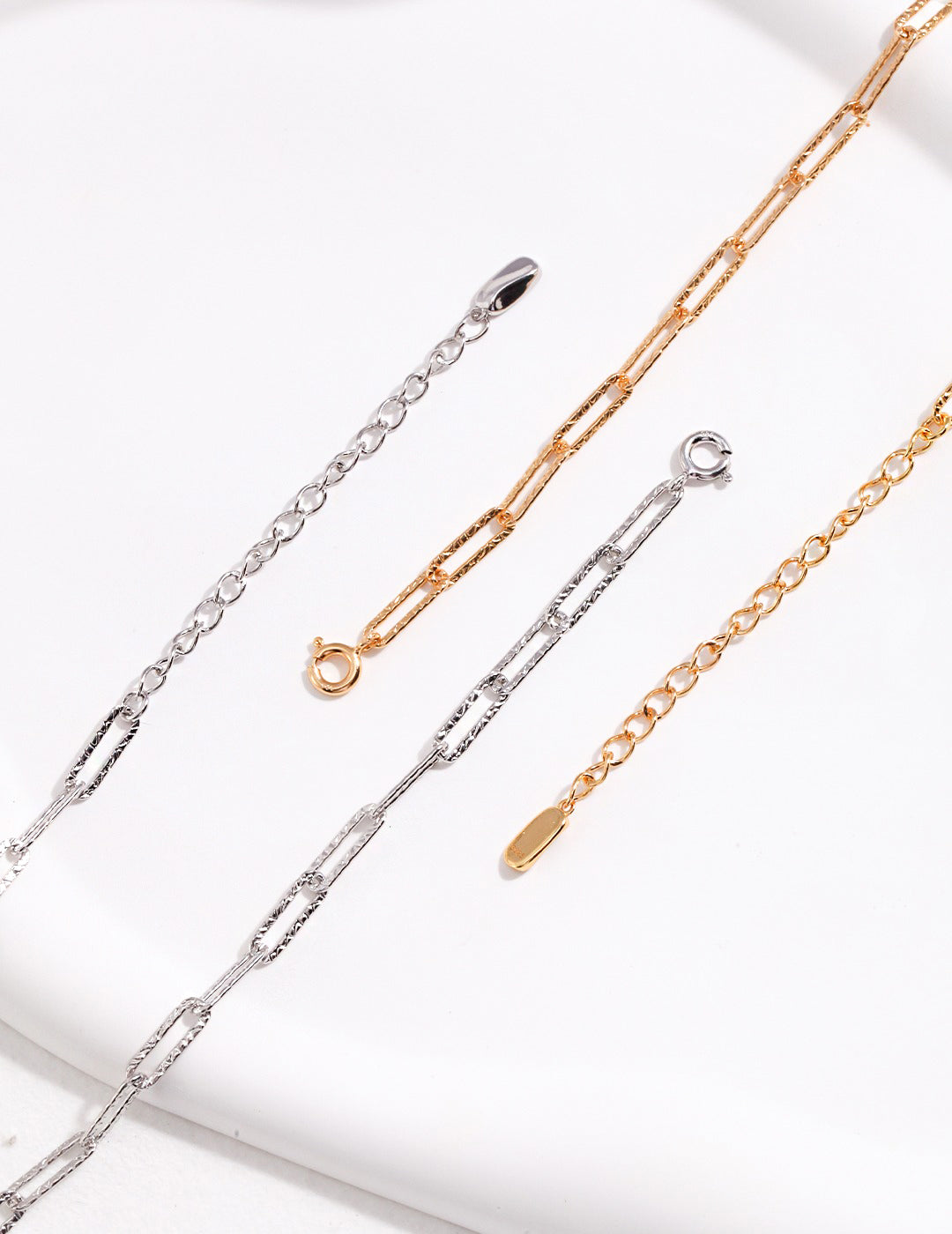 Silver and gold chain necklaces with unique links, captured in a close-up shot.
