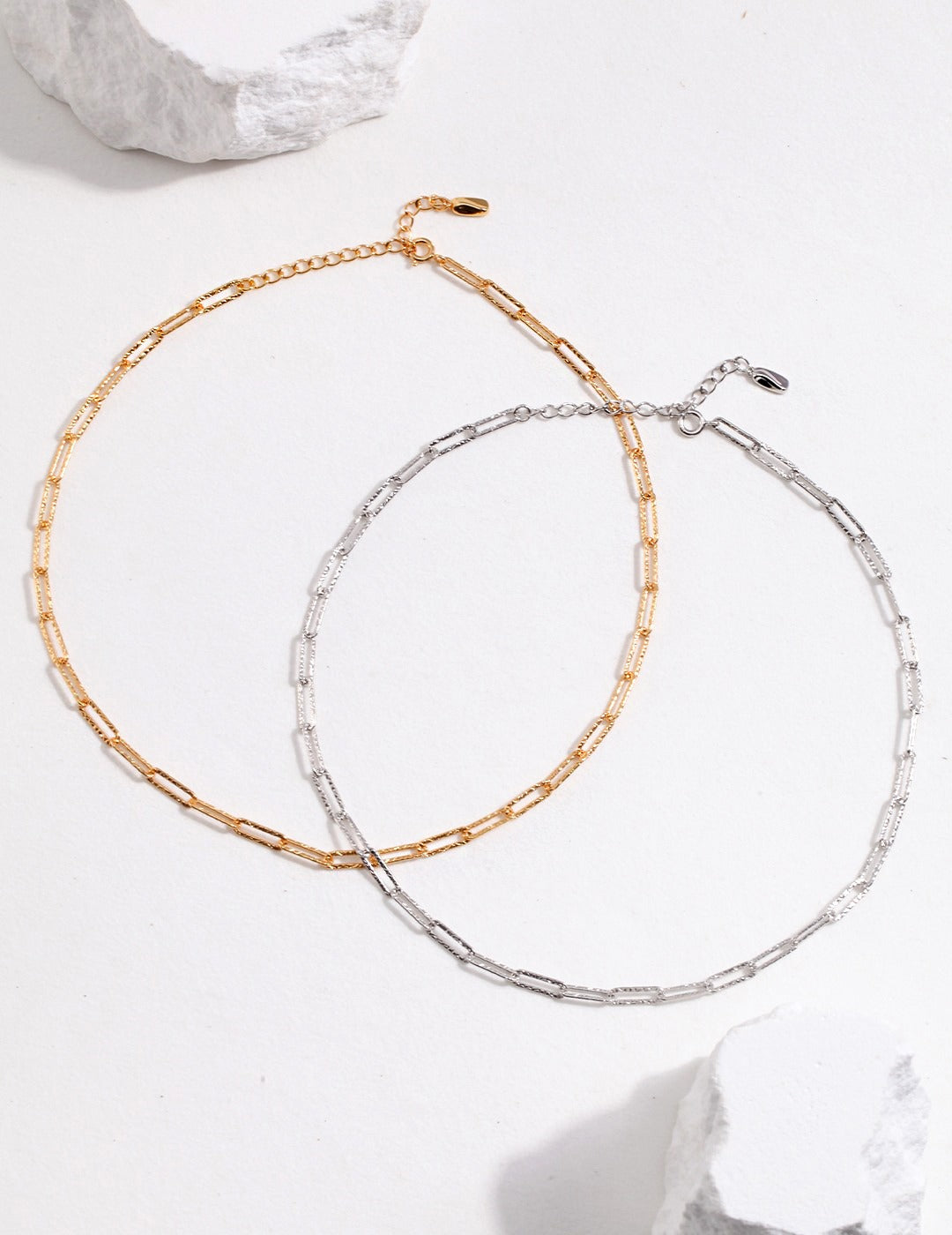 Two gold and silver link chain chokers on white background.