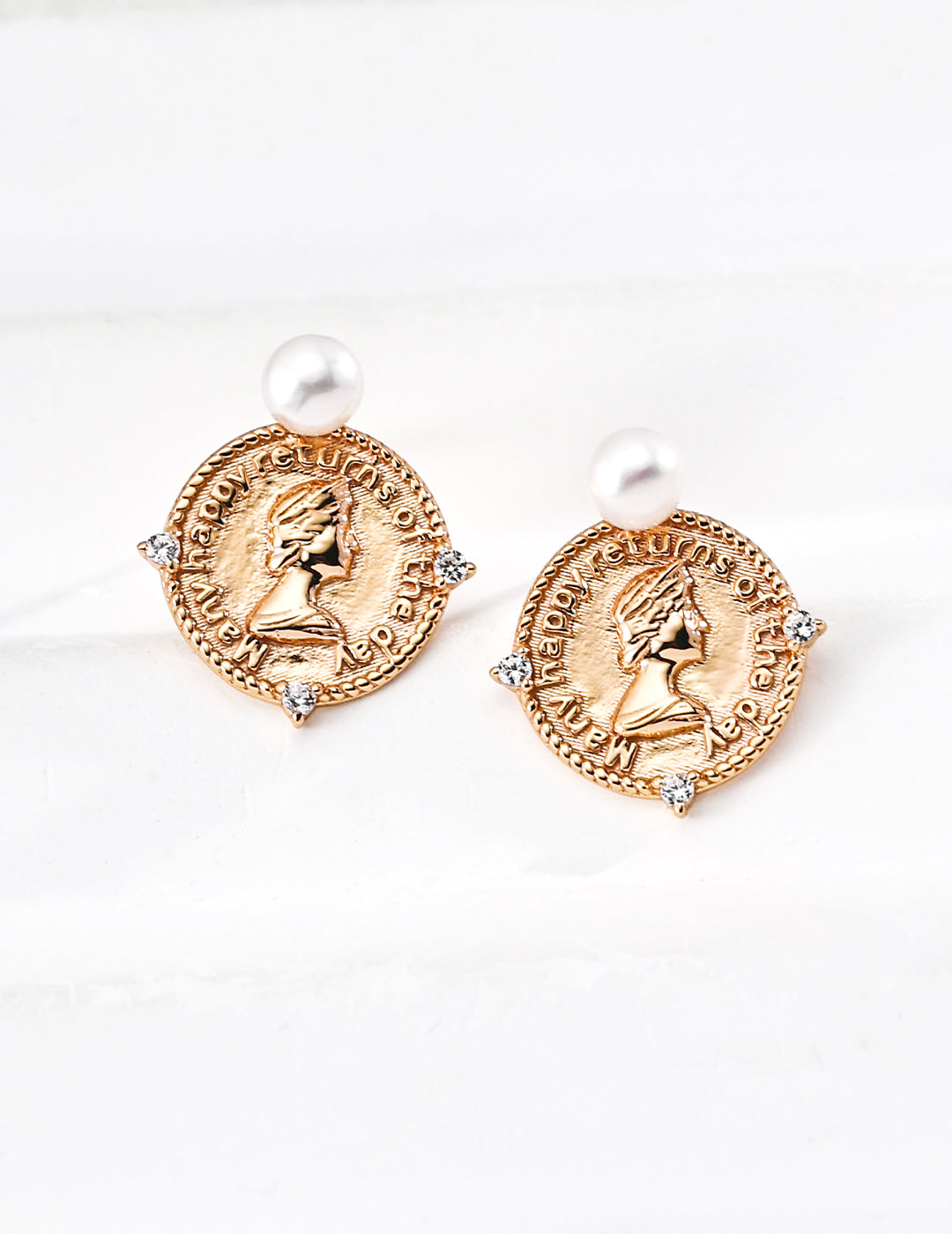 Circular gold coin-shaped studs (Louise Earrings) with freshwater pearls and zirconia in S925 Silver by Mezuille on white surface.