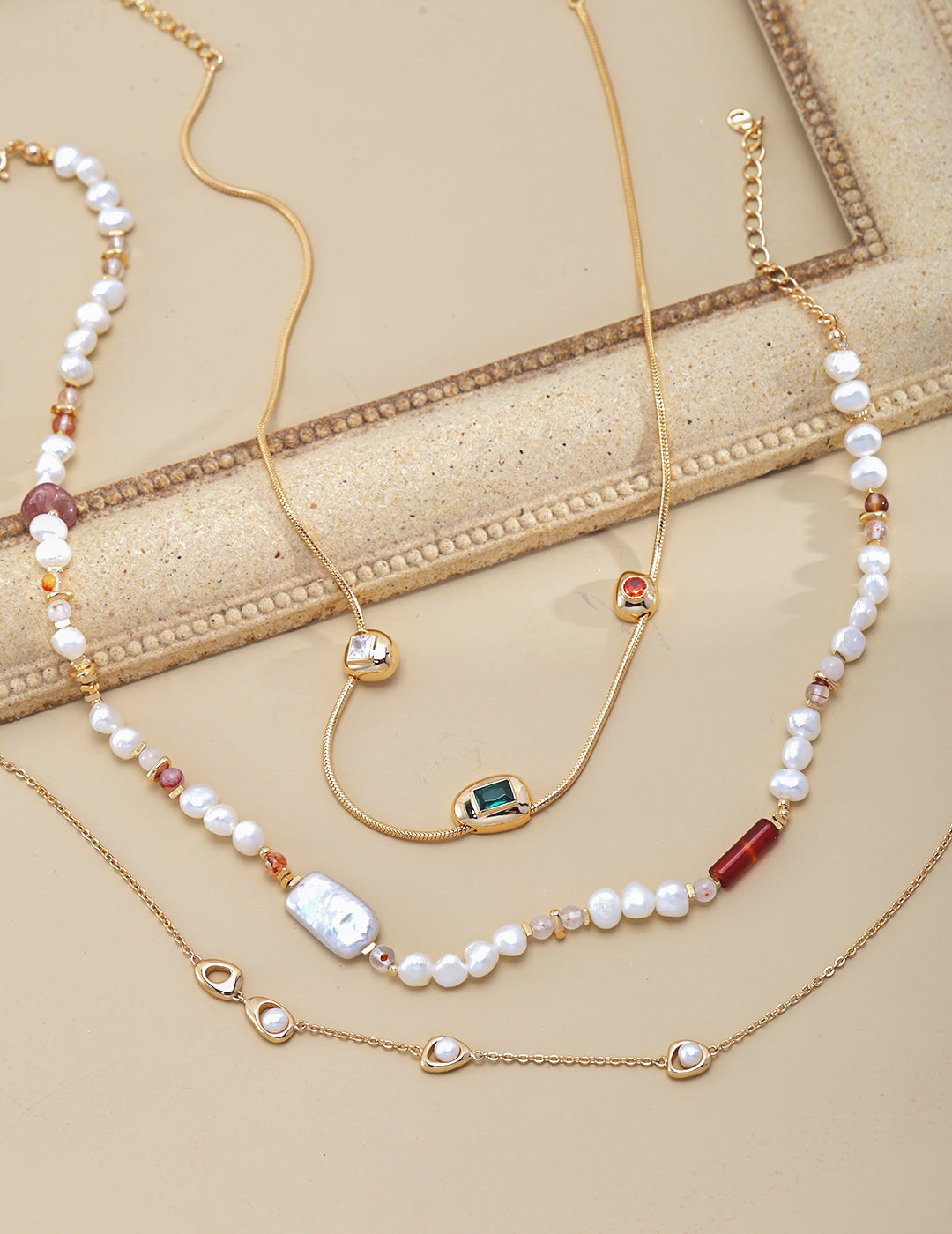 Three necklaces: freshwater pearl necklace with strawberry quartz, layered with a gold necklace.