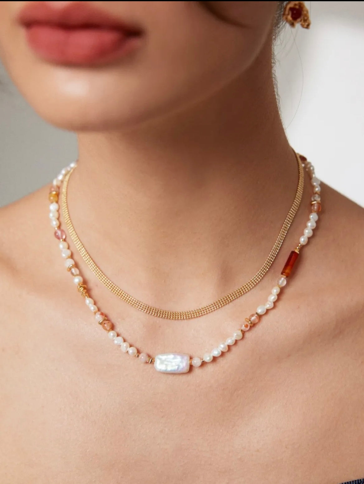 Layered necklace featuring pearls, a gold chain, and strawberry quartz accents for a stylish and elegant look.
