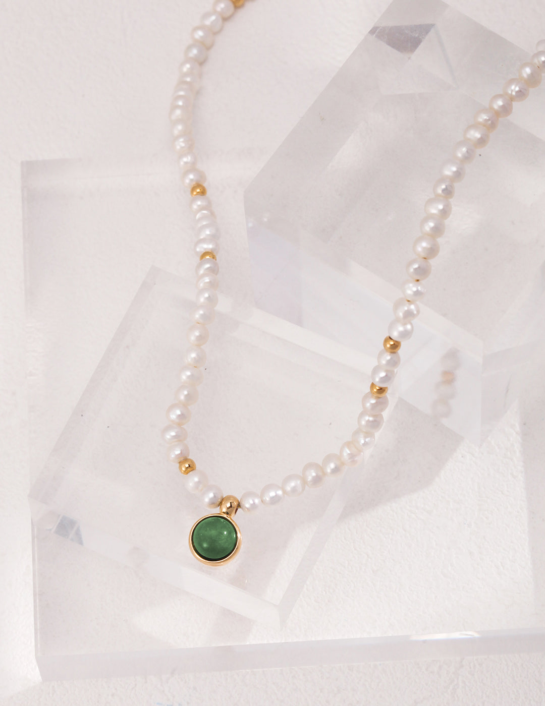 A vintage necklace with a green agate pendant and freshwater pearls.