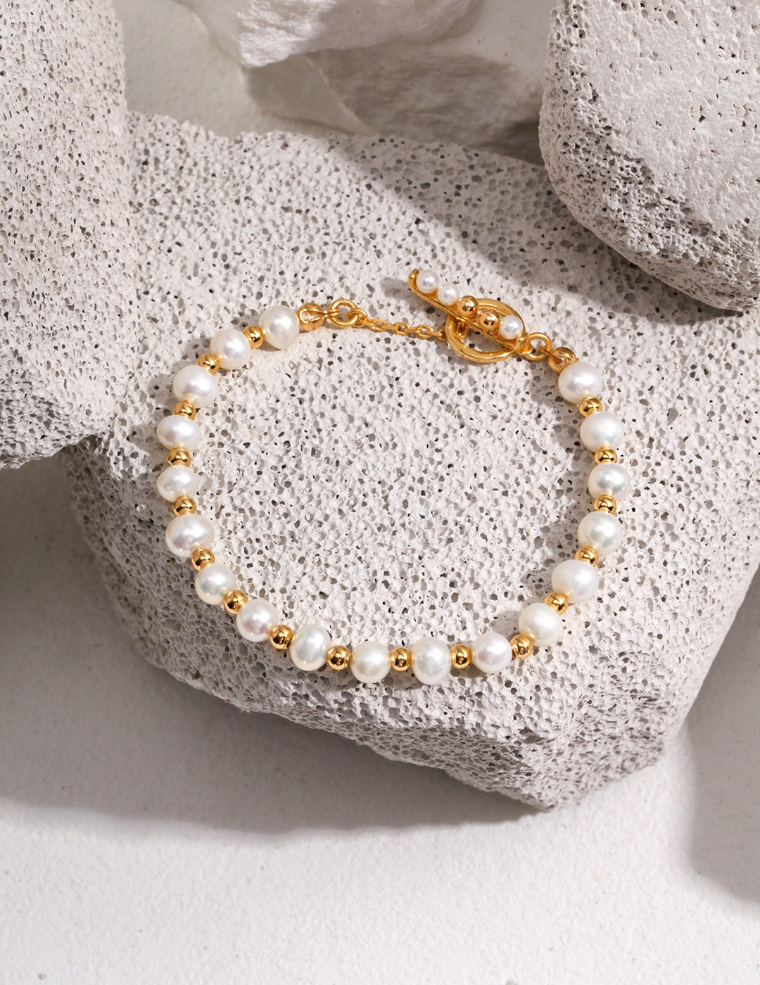 Elegant gold freshwater pearl bracelet on a rock