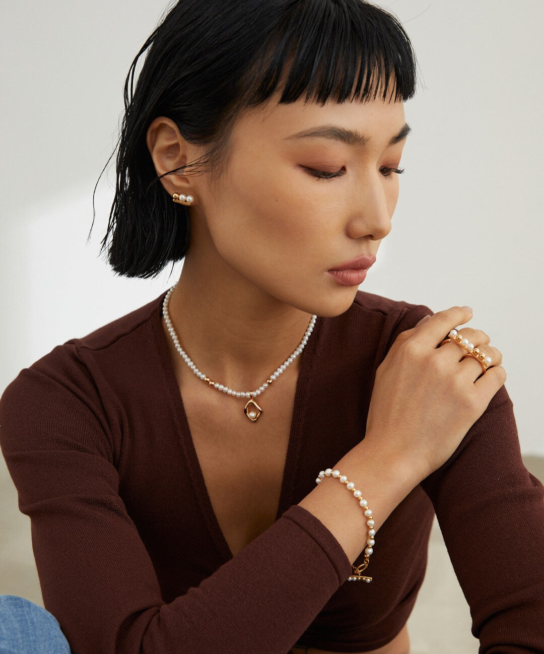 A stylish model showcasing a gold freshwater pearls bracelet, complemented by a beautiful necklace.