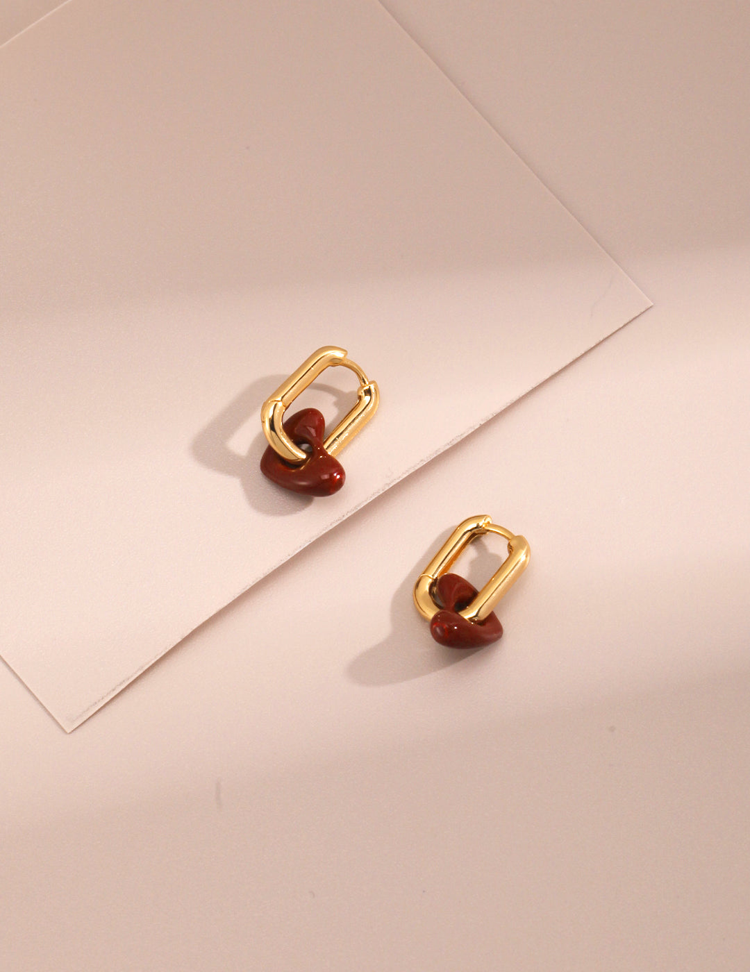 Stylish gold plated hoops featuring vibrant red heart accents.