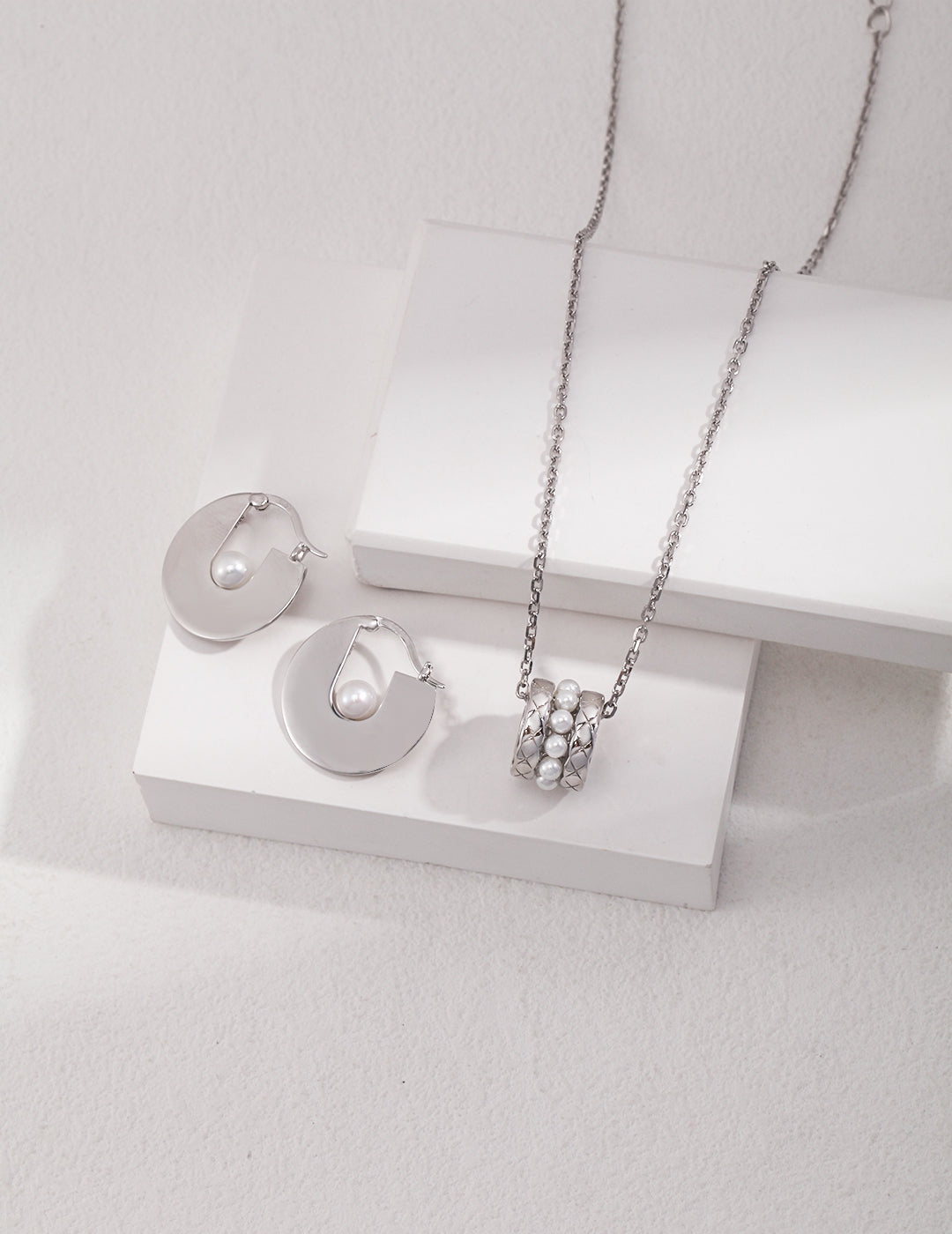 Stylish silver pearl accessories displayed on white.