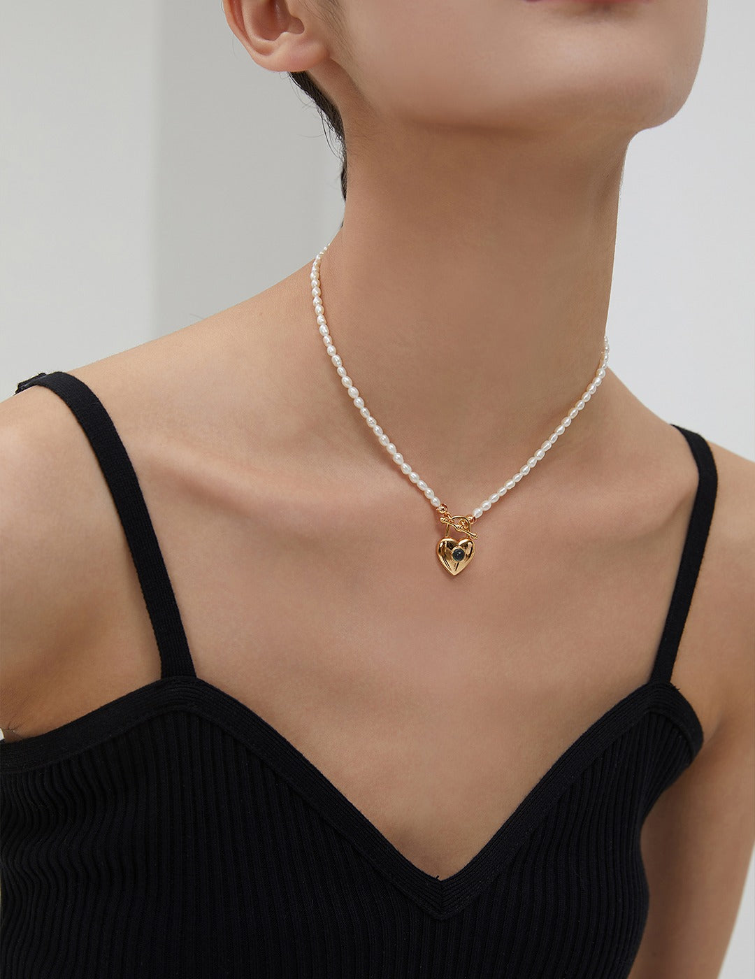 Elegant woman adorned with rice pearls and gold plated heart necklace.