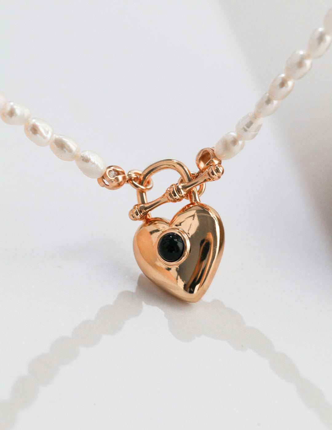Close-up of gold plated heart pendant on rice pearl necklace.