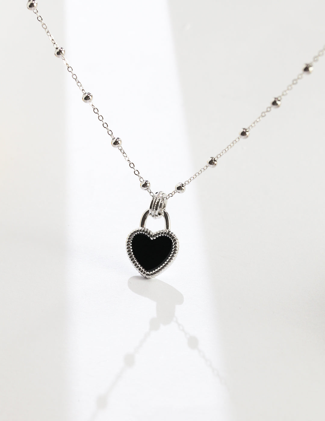 Black enamel heart pendant on silver chain necklace.
