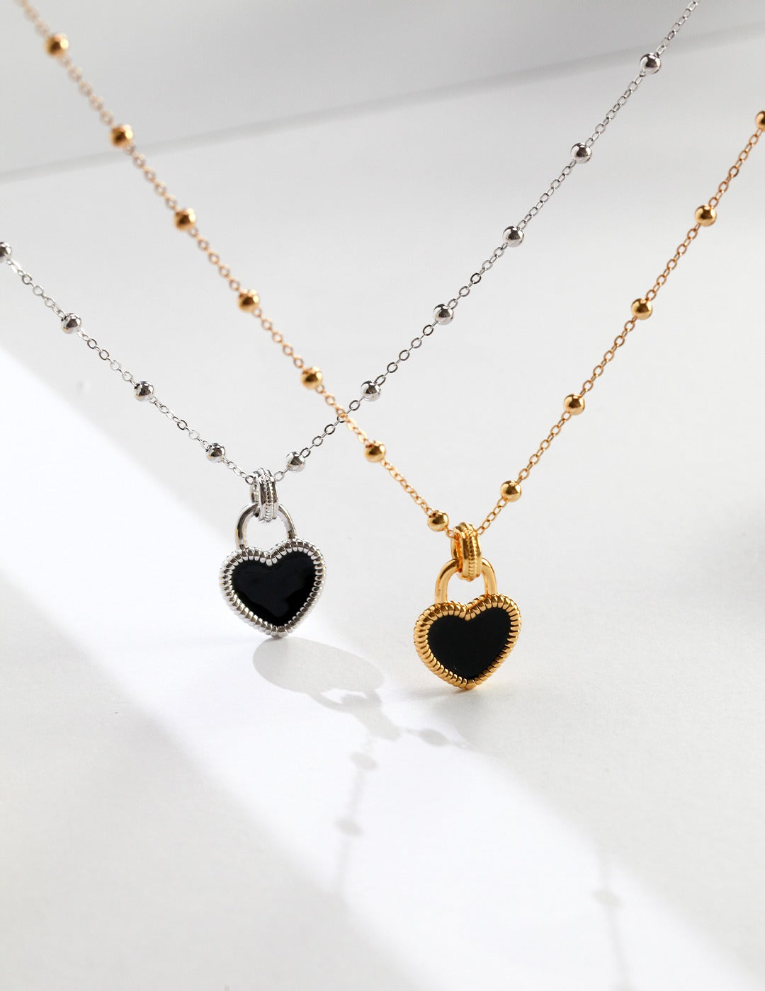 Black heart-shaped necklaces in silver and gold.