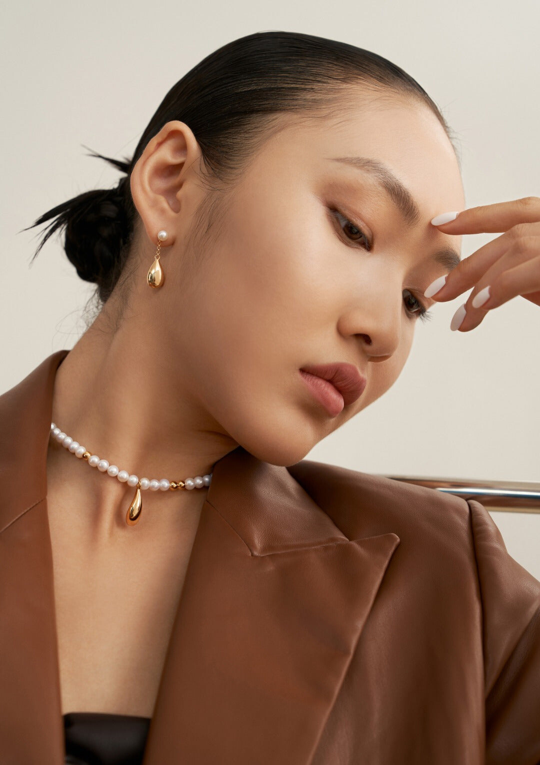 A model wearing a brown jacket and a gold plated freshwater pearls necklace.
