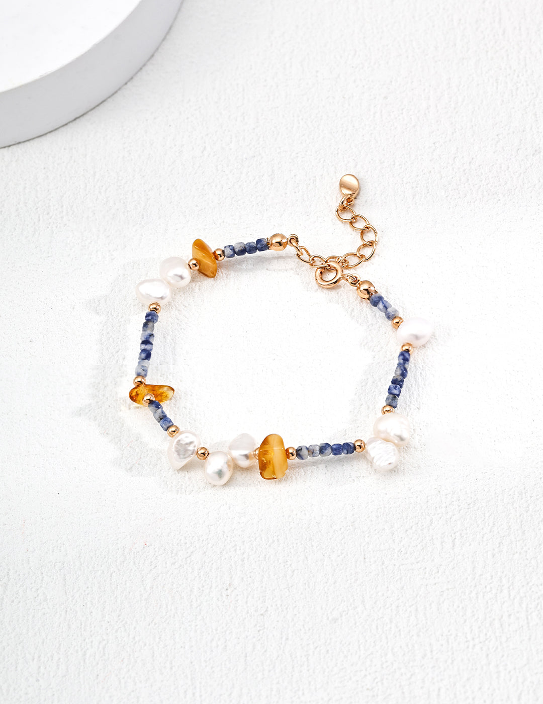 A stylish bracelet adorned with blue and yellow beads, a gold clasp, and elements of Azurite, beeswax, and freshwater pearls.