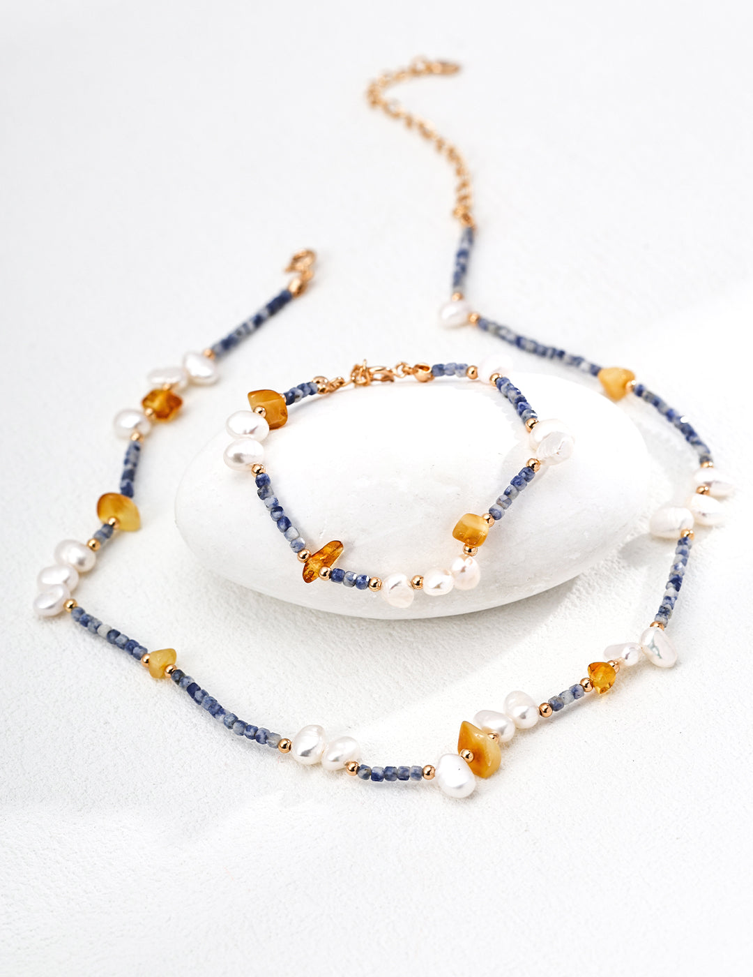 Set of a necklace featuring blue and yellow beads, crafted from Azurite in Granite, alongside a beeswax and freshwater pearl bracelet.