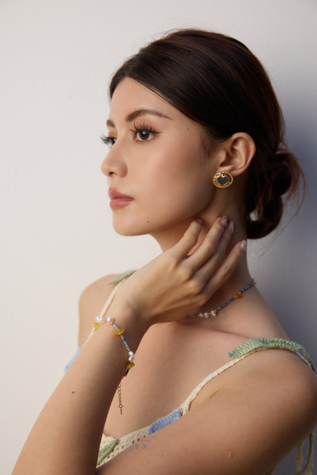 A woman showcases a matching necklace and bracelet made of Azurite in Granite, beeswax, and freshwater pearls.