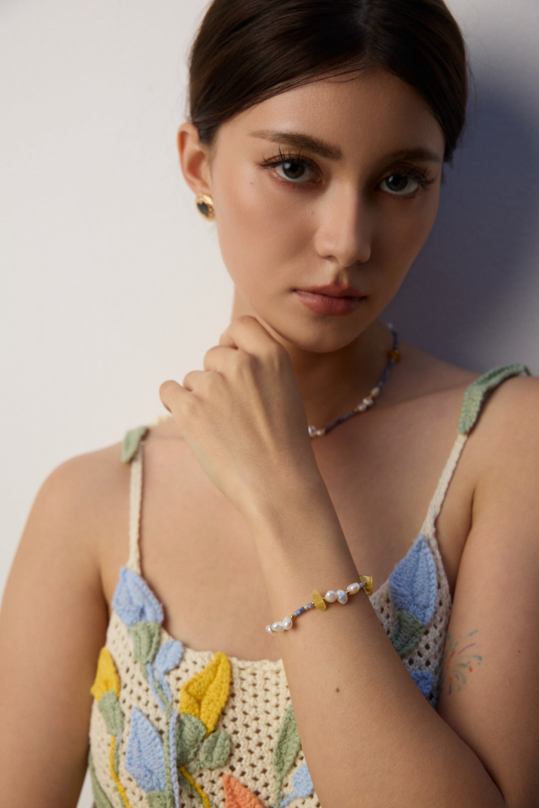 A woman in a vibrant floral dress, complemented by a matching necklace and bracelet, stands confidently.