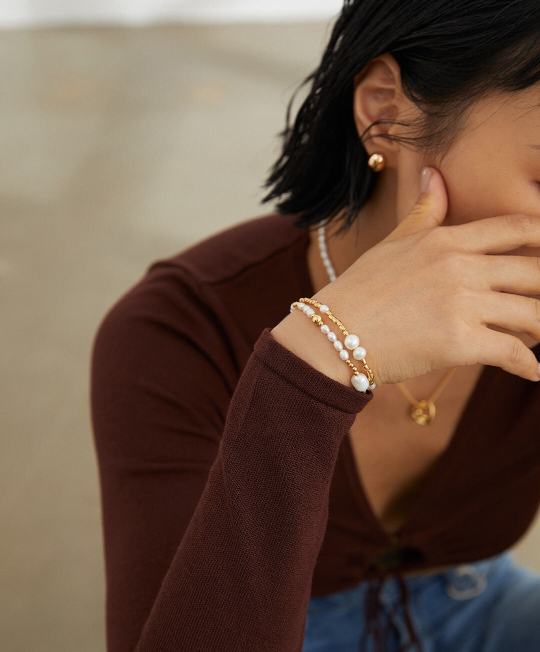Woman wearing gold beaded freshwater pearls bracelets and necklace.