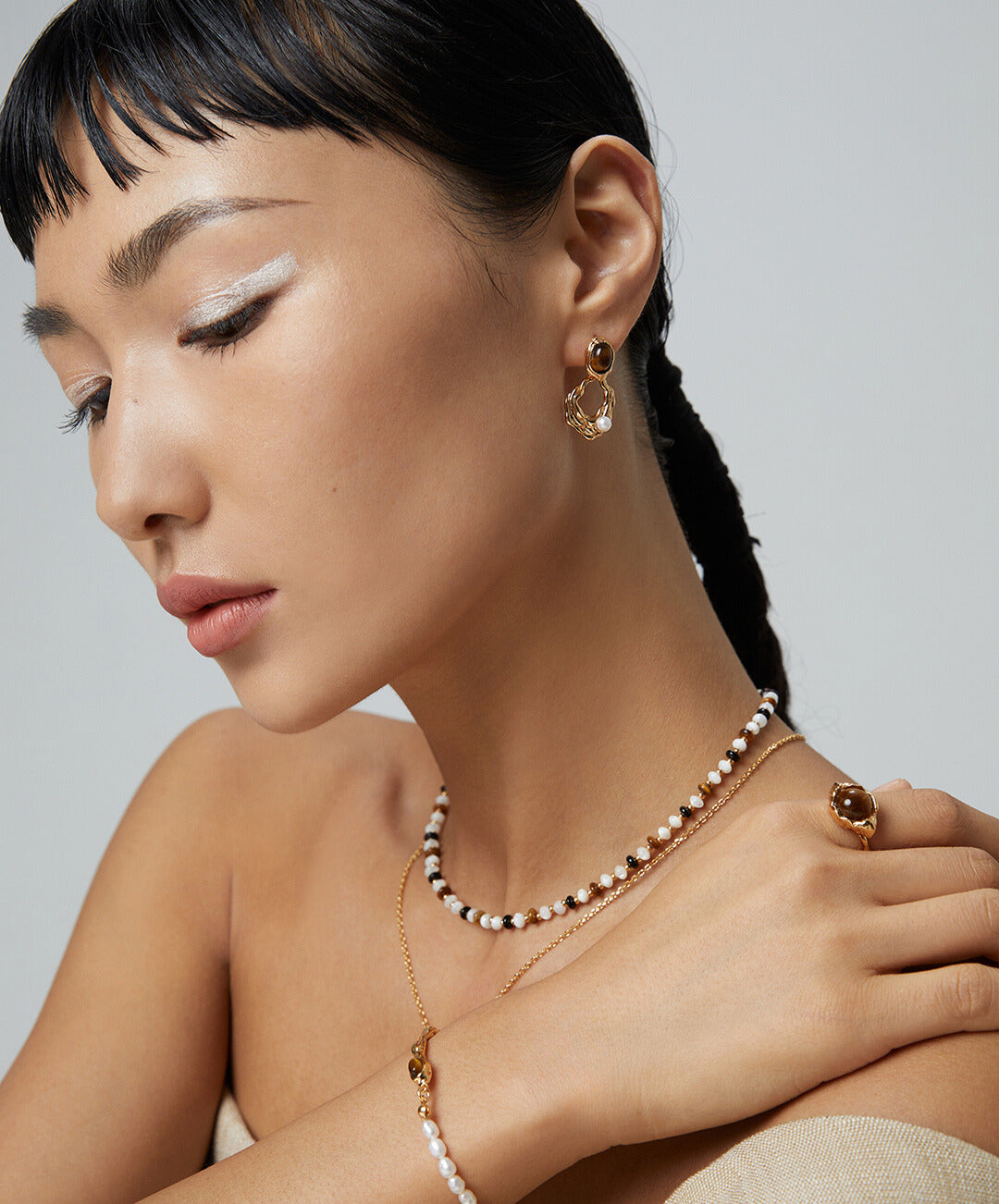 Elegant woman displaying necklace and bracelet set with tiger's eye stone and gold plated accents.