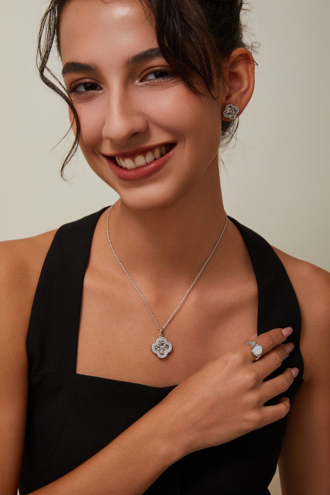 A woman wearing a silver clover pendant necklace and ring, presenting a chic jewelry look.