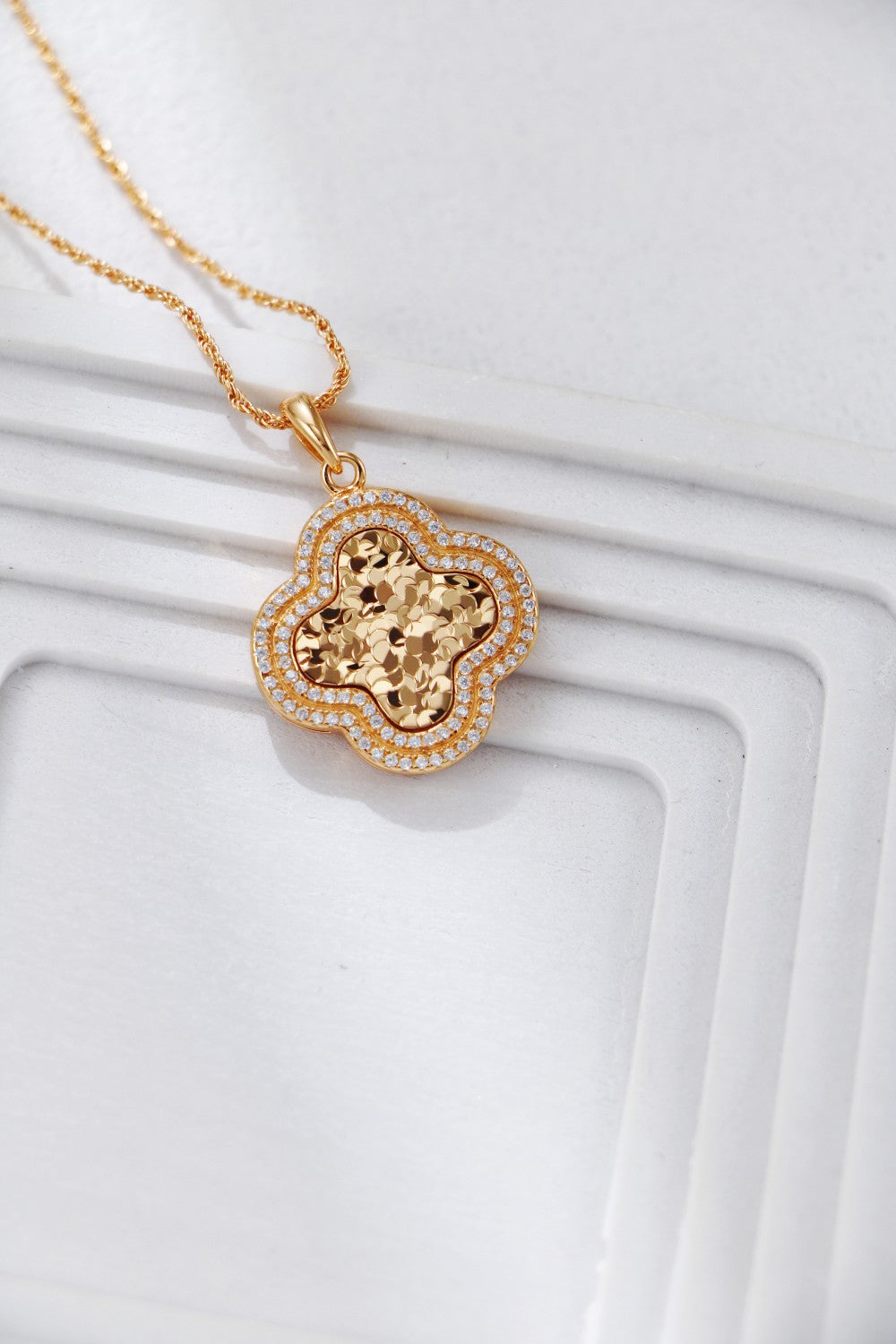 Detailed view of a gold-plated necklace with a clover flower pendant, showcasing its elegant design.