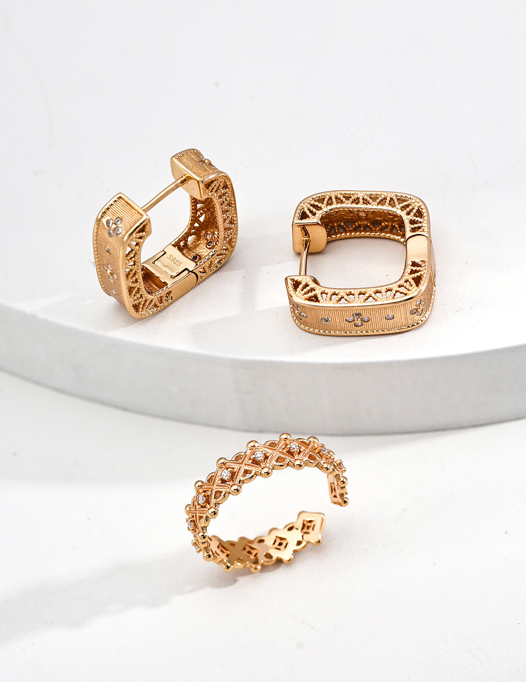 A set of three gold-tone jewelry with zirconia, showcasing a neat ring and matching hoop earrings for a chic look.