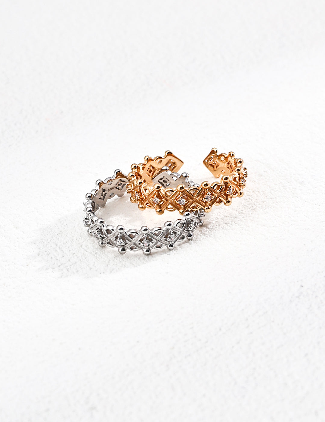 A pair of dainty gold and silver rings, featuring sparkling diamonds and zirconia, elegantly stacked together.