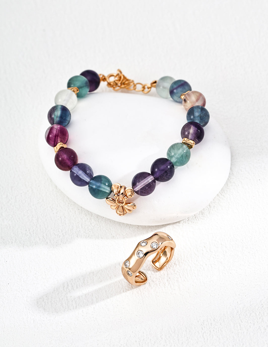 A vibrant fluorite bracelet with a gold ring and a prominent purple stone, highlighting its colorful appeal.