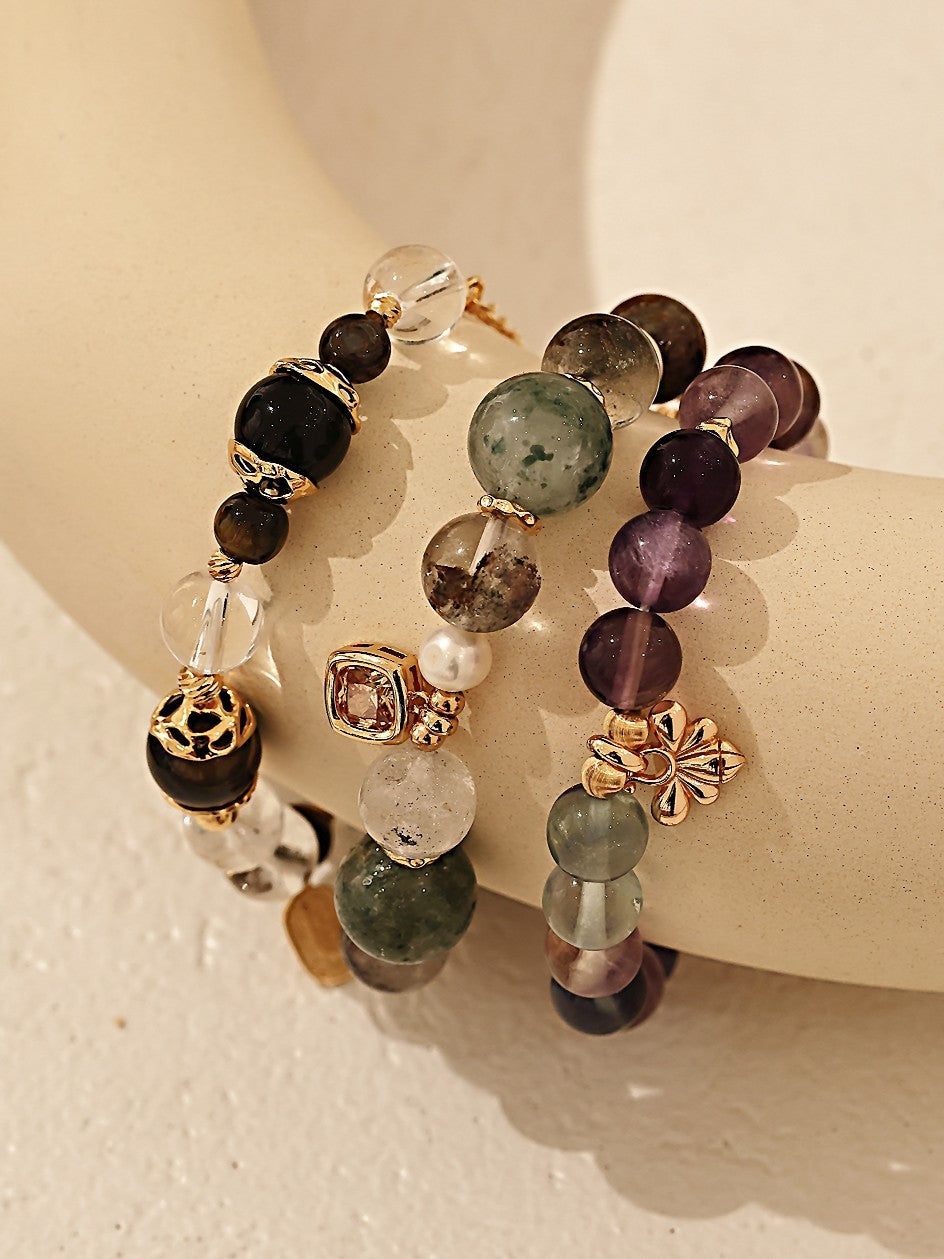 Multicolored beaded bracelet with gold accents on a wrist against a neutral background