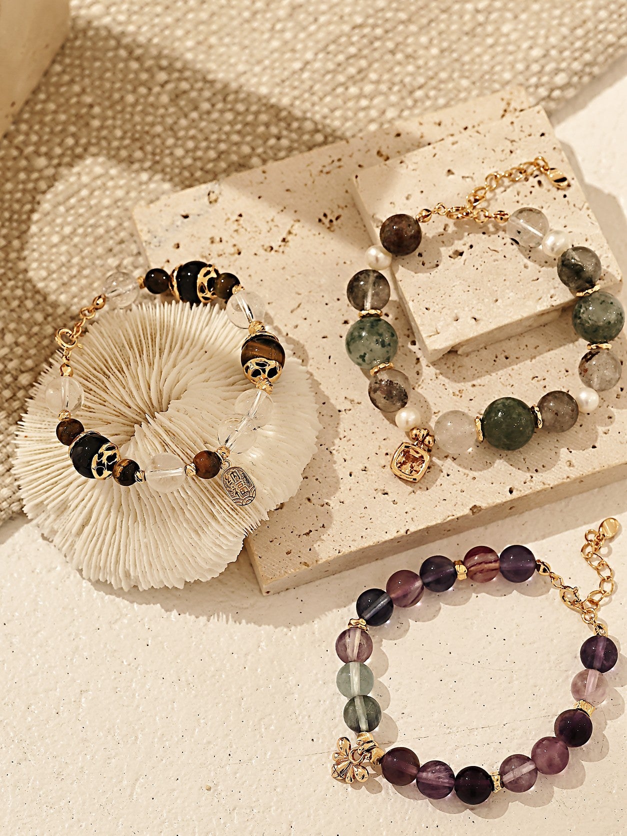 Three bracelets featuring various stones and gold chains, showcasing unique designs and colors.