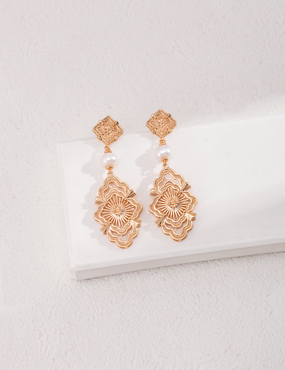 Intricately designed gold earrings with noble freshwater pearls.