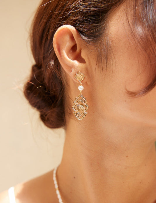 A woman showcasing elegant pearl and gold earrings, exuding a royal vibe with her sophisticated style.