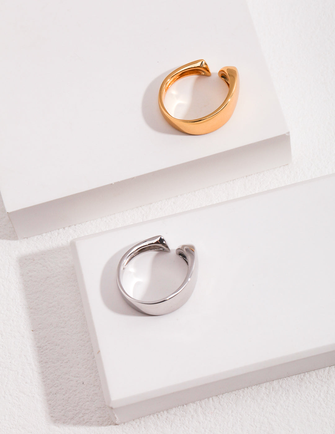 Shiny silver and gold rings on white background.