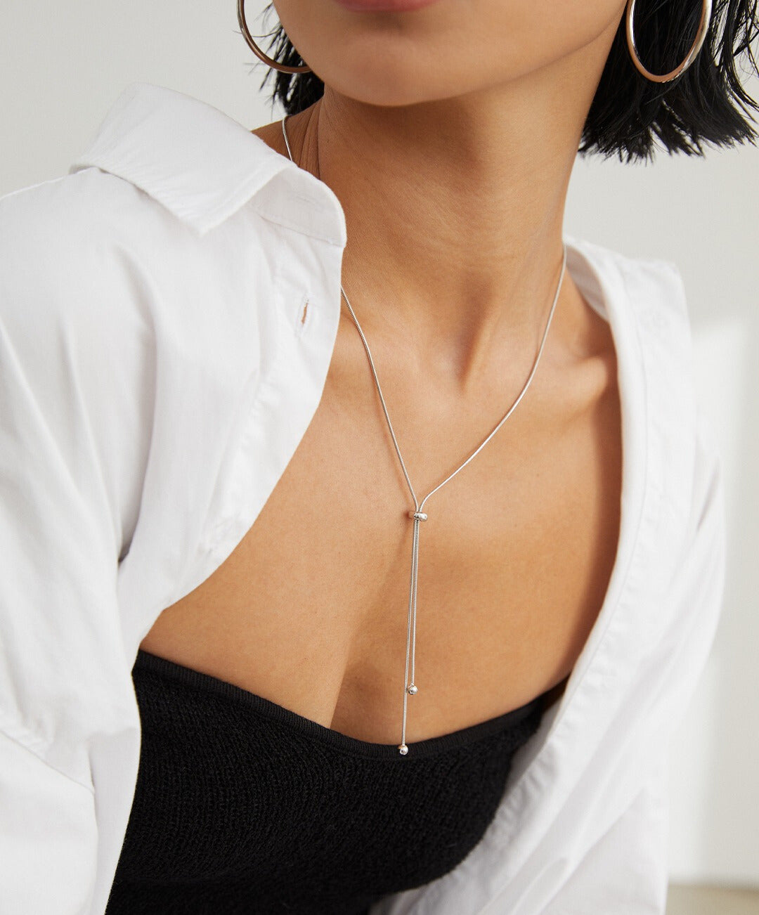 Woman wearing white shirt and silver necklace.