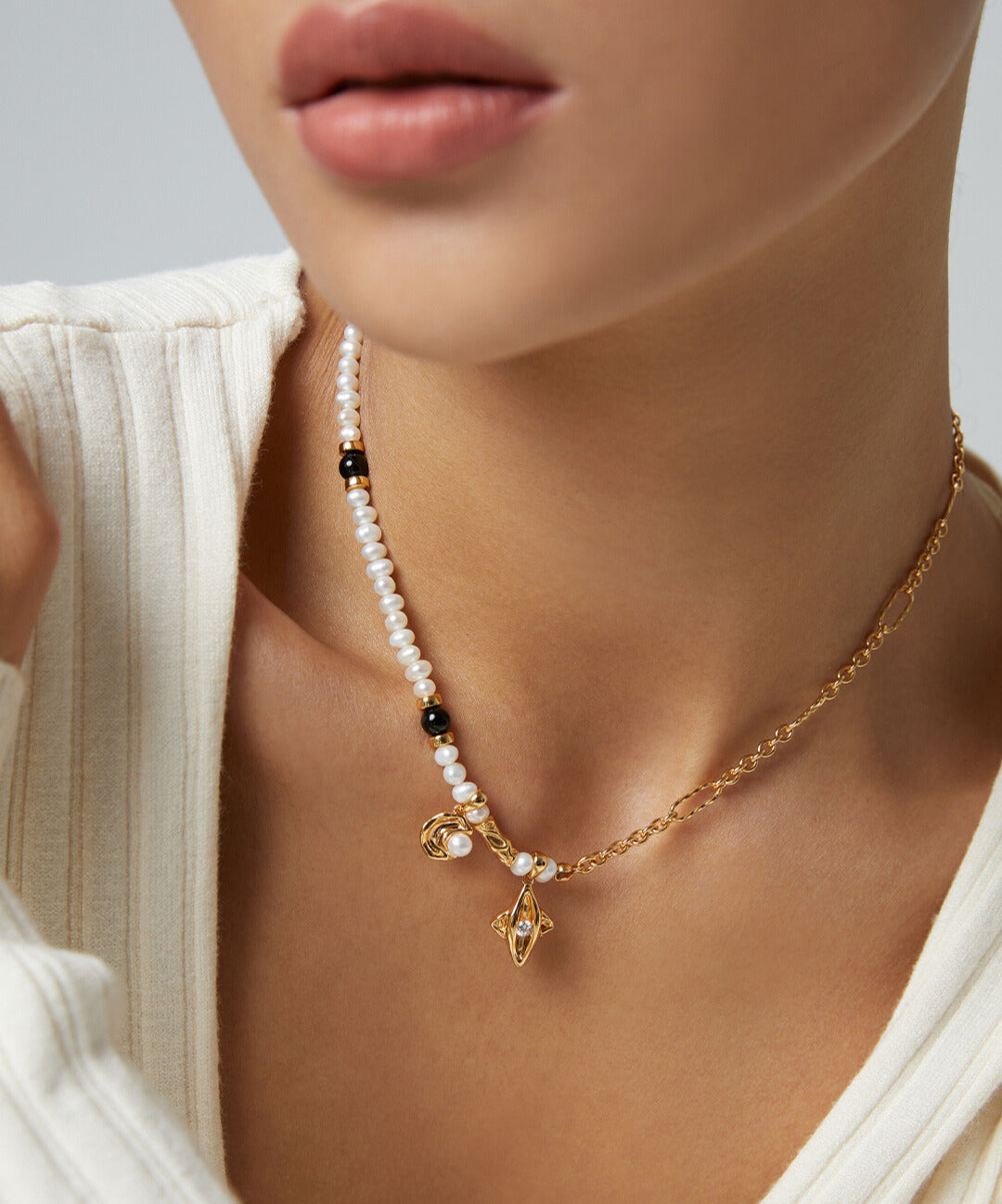 Model showcasing gold chain necklace adorned with celestial elements and pearls.