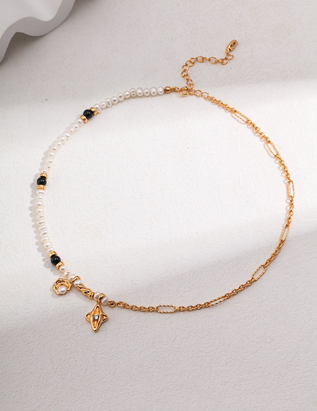 A celestial-inspired gold chain necklace adorned with a lustrous pearl and elegant black beads.