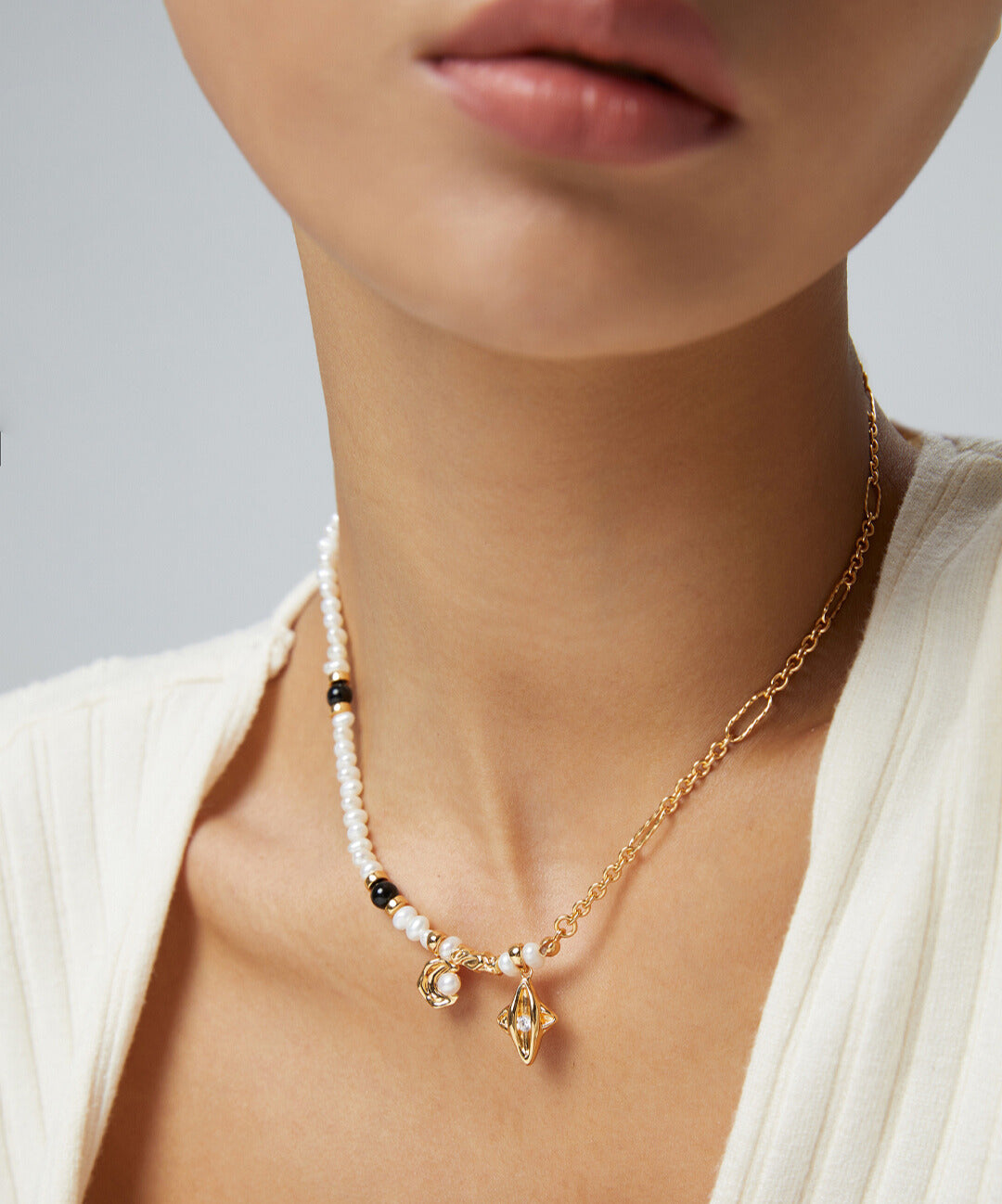 Model showcasing gold chain necklace adorned with celestial elements and pearls.